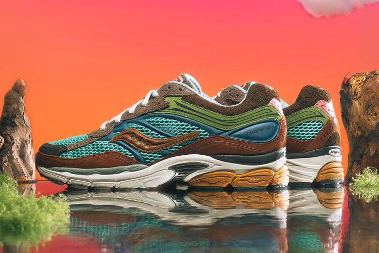 Dve retro a robustné viacfarebné bežecké tenisky Saucony ProGrid Omni 9 umiestnené na reflexnom povrchu s kameňmi a ružovo-oranžovým gradientným pozadím.